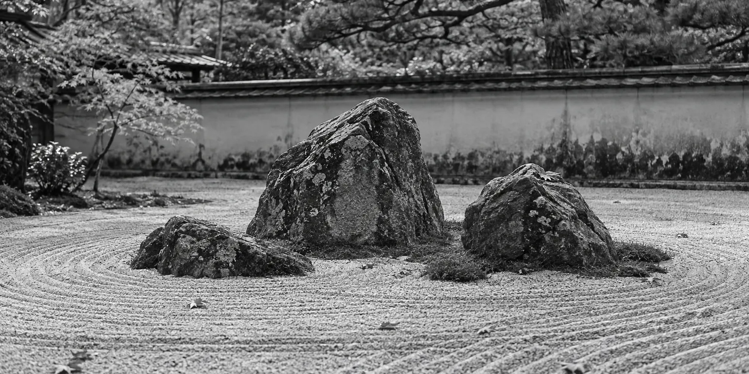 Black and white Japanese Zen garden with curved lines of raked gravel, weathered rocks, and pine trees.